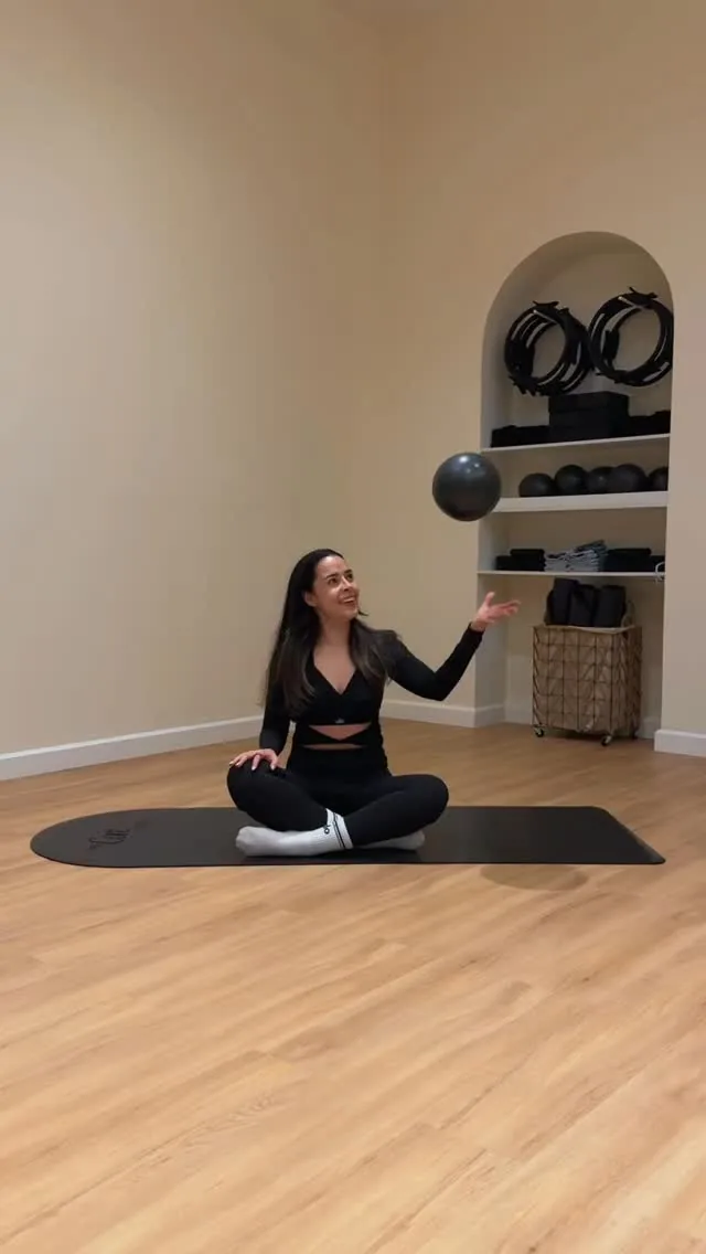 Instructora de Pilates sentada sobre una colchoneta en el estudio